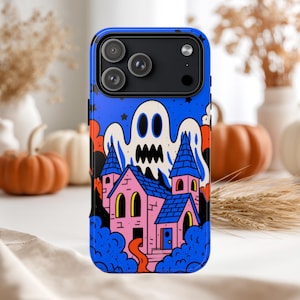 May include: A smartphone case featuring a vibrant graphic illustration of a pink house with blue roofs, surrounded by blue clouds and a large white ghost with black eyes and a jagged mouth against a dark blue starry night sky background.