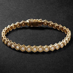 May include: A gold-toned bracelet featuring a series of connected hexagonal links, each containing a small, round, clear stone set in the center. The piece includes a secure metal box clasp mechanism at the top to fasten the circular chain.