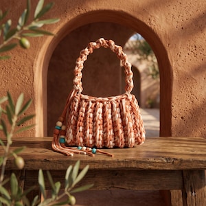May include: A crochet handbag featuring a ribbed texture in alternating shades of terracotta and cream. The bag has a braided handle and a side tassel adorned with wooden and turquoise beads, showcasing a handcrafted design with a soft, knotted finish.