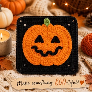May include: A square crochet motif featuring a bright orange jack-o'-lantern with a green stem centered on a solid black background. The pumpkin has two black triangular eyes and a wide, wavy black mouth stitched into the center of the square.