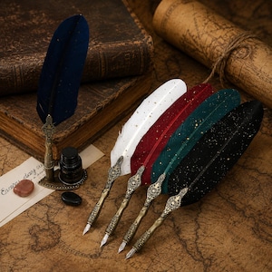 May include: A collection of five quill pens featuring metallic, ornate handles with intricate engravings and silver-toned nibs. The feathers come in blue, white, red, green, and black, each accented with gold-colored speckles. A small ink bottle is included.