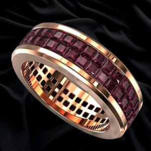 May include: A rose gold band ring featuring a central channel set with two rows of square-cut deep red gemstones. The metal has a polished finish, and the interior of the band displays a grid-like pattern consistent with the stone settings.