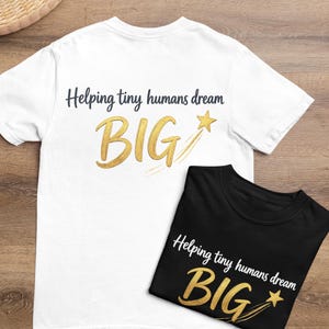 Puede incluir: Una camiseta blanca y una camiseta negra, ambas con el texto "Helping tiny humans dream BIG" en una fuente oscura, con la palabra "BIG" en un estilo de pincelada dorada acompañada de un gráfico de estrella fugaz dorada.