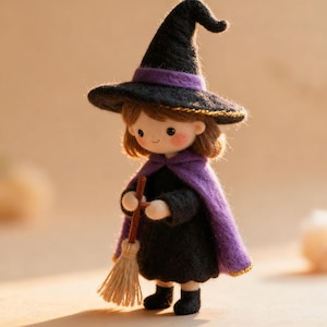 Puede incluir: Una muñeca de fieltro de aguja vestida de bruja, con un sombrero negro puntiagudo con una banda morada, una capa morada y un vestido negro. La muñeca tiene el pelo castaño, mejillas sonrosadas y sostiene una pequeña escoba marrón con cerdas beige.