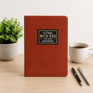 May include: A rust-colored, leather-textured devotional book with a rectangular black label on the front cover. The label features gold text that reads One Minute WITH GOD FOR MEN 365 DAILY DEVOTIONS. The book has a clean, vertical orientation.