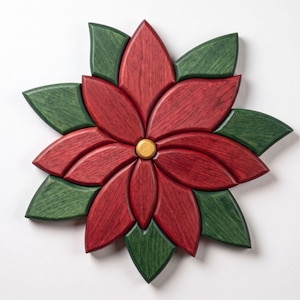 May include: A decorative wall hanging shaped like a poinsettia flower, crafted from wood. The piece features deep red petals and dark green leaves arranged in a star pattern, with a small, smooth, light-coloured circular wooden centre piece.
