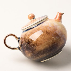 May include: A ceramic teapot featuring a rounded body with a mottled glaze in shades of brown, tan, and dark blue. The teapot includes a matching lid with a small knob handle, a curved spout, and a side handle, all finished with a glossy texture.