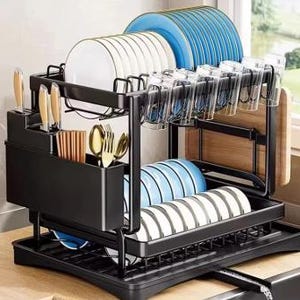 Pode incluir: Um escorredor de louça de dois níveis em metal preto, com uma prateleira superior para pratos e copos, uma prateleira inferior para tigelas e compartimentos laterais para facas, talheres e uma tábua de corte. Inclui uma bandeja de gotejamento.