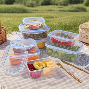 Peut inclure: Un ensemble de boîtes de conservation alimentaires rectangulaires en plastique transparent avec des joints en silicone bleu clair sur les couvercles. Elles contiennent divers fruits et légumes frais, dont des carottes, du raisin, de l'avocat et du melon.