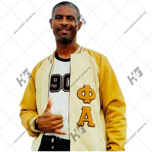 May include: A gold and cream varsity jacket featuring the Greek letters Phi and Alpha in gold felt appliqué on the chest. The jacket is worn over a white t-shirt with the number 90 printed in black with a gold outline on the front chest area.