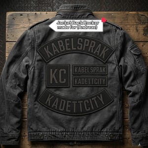 Może przedstawiać: Ciemnoszara kurtka z nadrukiem na plecach z tekstem KABELSPRAK, KC, KADETTCITY oraz białą etykietą z napisem Jacket Back Rocker made for (Andreas). Kurtka posiada stójkę, długie rękawy oraz zapięcia na guziki przy pasie.