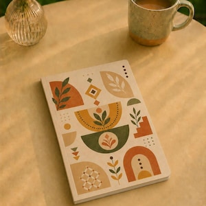 Puede incluir: Un cuaderno rectangular con una cubierta de color crema que presenta un patrón geométrico de hojas, arcos y puntos en tonos terracota, verde salvia y beige. El diseño incluye varias formas abstractas, líneas y pequeñas ilustraciones botánicas.