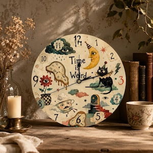 May include: A round wall clock with a cream-colored face featuring the text Time is Weird. The design includes illustrations of a melting clock, a crescent moon with a face, a black cat, a teacup with a face, a flower with an eye, and clouds.
