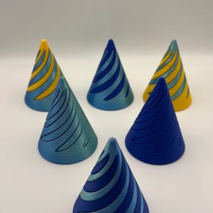 May include: Six conical objects arranged in a group, each featuring a distinct spiral pattern. The cones display various shades of blue, teal, and yellow, with some featuring dual-tone colour combinations and others in solid colours with recessed grooves.