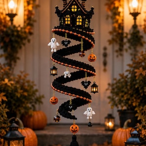 May include: A black crocheted spiral hanging decoration featuring a haunted house top, a gold crescent moon, and dangling charms including white ghosts, orange pumpkins, black bats, and small lanterns, finished with a black tassel at the bottom.
