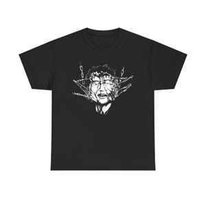 May include: A black short-sleeve t-shirt featuring a white graphic print on the chest. The design depicts a human face with curly hair, surrounded by and partially obscured by several thin, dangling metal chains that appear to pierce the skin.