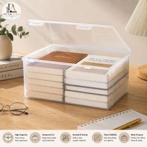 Puede incluir: Una caja de almacenamiento rectangular de plástico transparente con tapa abatible, que contiene dos pilas de cuadernos. Los cuadernos superiores muestran el texto "JOURNAL" y "Life is a collection of beautiful moments".