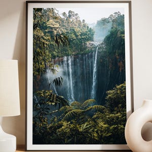 May include: A framed wall art print featuring a vertical landscape photograph of a tall waterfall cascading down a lush, green cliffside surrounded by dense tropical forest foliage, with the text NO IA ORIGINAL PHOTO MADE BY HUMAINS DIGITAL DOWNLOAD.