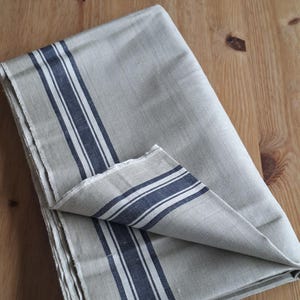 May include: A white ceramic mug with a black handle and the text "But First, Coffee" in a bold, black font. The mug is set against a blurred background, suggesting a cosy setting.