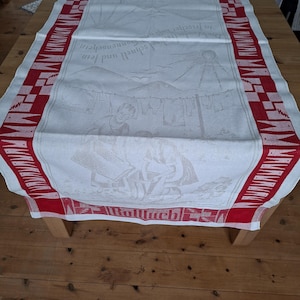 Könnte beinhalten: Eine weiße Keramik-Tasse mit schwarzem Henkel und dem Text "But First, Coffee" in schwarzer, handschriftlicher Schrift. Die Tasse steht auf einer weißen Oberfläche.