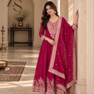 May include: A magenta floor-length dress with long sleeves, featuring intricate silver embroidery around the neckline, cuffs, and hem. The garment includes a matching sheer magenta dupatta with silver border detailing and small scattered motifs.