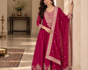 May include: A magenta floor-length dress with long sleeves, featuring intricate silver embroidery around the neckline, cuffs, and hem. The garment includes a matching sheer magenta dupatta with silver border detailing and small scattered motifs.