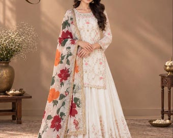 May include: An off-white three-piece ensemble featuring a long-sleeved tunic and a floor-length pleated skirt, both adorned with delicate floral embroidery. A sheer dupatta with large red and orange floral prints and gold trim completes the set.
