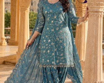 May include: A teal blue salwar kameez set featuring a long-sleeved tunic and matching pleated trousers. The fabric is adorned with intricate silver embroidery and small reflective mirror accents. A coordinating sheer dupatta with scalloped edges.