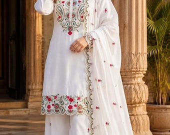 May include: A white three-piece outfit consisting of a long-sleeved tunic, wide-leg trousers, and a matching dupatta. The set features intricate floral embroidery in red, green, and gold thread, with scalloped edges along the hem and cuffs.