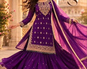 May include: A deep purple sharara suit featuring intricate gold embroidery on the long-sleeved tunic and a matching flared skirt. The ensemble includes a sheer purple dupatta with gold trim, and the letters ZS are visible in the upper right corner.
