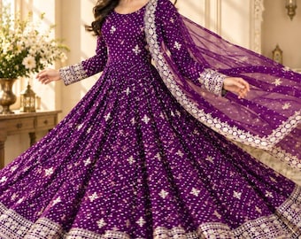 May include: A deep purple floor-length gown featuring long sleeves, a round neckline, and an all-over pattern of small white and gold embroidered motifs. The hem and cuffs are adorned with wide, intricate gold metallic bands and embroidery.