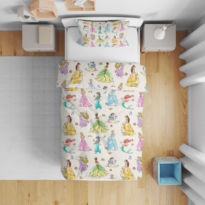 Può includere: Un letto singolo con copripiumino bianco e federa abbinata, caratterizzato da una stampa ripetuta in stile acquerello di varie principesse animate in abiti colorati, tra cui vestiti gialli, blu, verdi e rosa su uno sfondo chiaro.