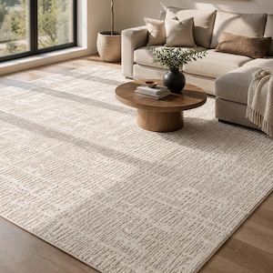 May include: A rectangular area rug featuring a textured, off-white and beige geometric pattern composed of repeating linear blocks. The rug has a low-pile construction with a subtle, raised relief design that creates a grid-like visual effect across the surface.