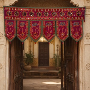 May include: A magenta fabric door valance featuring embroidered blue elephant motifs and floral patterns. The rectangular top border is decorated with circular mirrors and flower designs, while six pointed panels hang below with green trim.