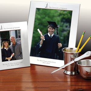 May include: Two silver picture frames with a graduation photo in each. The top frame has the text "The University of Vermont" and "The Best Years of Our Lives 2011-2015". The bottom frame has the text "The University of Vermont" and "We Are So Very Proud of You! Love, Mom & Dad".
