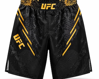 Könnte beinhalten: Schwarze Sportshorts mit gelbem UFC-Schriftzug am Bund und am linken Bein. Das Design umfasst gelbe diagonale Streifen, ein dezentes dunkelgraues Schlangenhautmuster auf dem Stoff und seitliche Schlitze am unteren Saum.