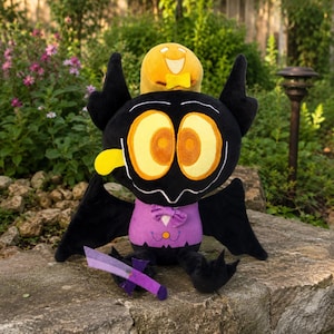 May include: A black plush creature with large yellow eyes, a purple vest, and a yellow tongue. It wears a purple bow tie and holds a purple sword. A small yellow round plush with a smiling face and a yellow bow tie sits on its head.