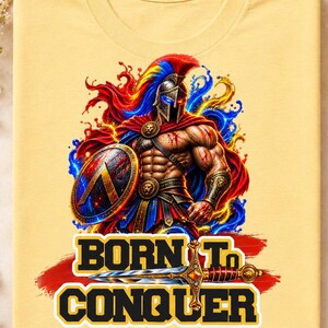 May include: A light yellow t-shirt featuring a graphic of a muscular warrior in a spartan helmet, red cape, and armour, holding a shield. Behind the warrior are red and blue paint splashes. The text BORN TO CONQUER is printed in bold yellow letters.
