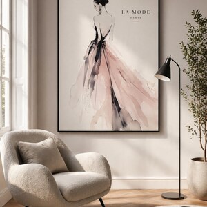 Puede incluir: Una lámina de arte enmarcada con una ilustración en acuarela de una figura con un vestido fluido y sin espalda, con pinceladas en rosa suave y gris oscuro. El texto LA MODE PARIS aparece en la esquina superior derecha sobre un fondo crema.