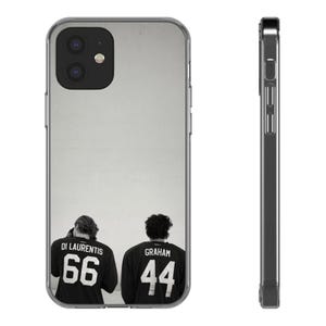 May include: A clear phone case featuring a black and white graphic of two individuals wearing jerseys with the names DI LAURENTIS 66 and GRAHAM 44 printed on the back. The case shows both the rear view and the side profile of the device.