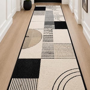 Peut inclure: Un long tapis de couloir rectangulaire présentant un motif géométrique composé de blocs noirs, blancs et beiges. Le design inclut des carrés pleins, des segments de lignes parallèles et des motifs en arc. Le tapis a une bordure noire.