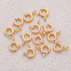 Peut inclure: Un ensemble de douze fermoirs à ressort de couleur dorée. Chaque apprêt de bijouterie circulaire présente un petit mécanisme à levier à ressort et un point de fixation à anneau fixe, conçu pour attacher des colliers, bracelets ou autres bijoux.