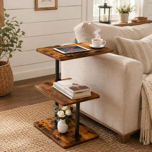 May include: A three-tier side table with a dark brown wood-grain finish and a black metal frame. The top shelf holds a tablet, the middle shelf holds a stack of books, and the bottom shelf holds a small white vase with white flowers.