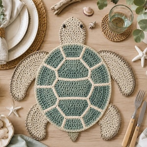 Puede incluir: Un mantel individual de ganchillo con forma de tortuga que presenta un caparazón central con segmentos hexagonales de color verde oscuro delineados con hilo color crema. La cabeza y las cuatro aletas son de hilo beige claro con dos cuentas oscuras.