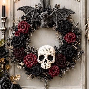 May include: A circular wreath featuring a crocheted gray bat at the top, a central cream-colored crocheted skull, and an arrangement of deep red and black crocheted roses interspersed with metallic silver-toned leaves and small branches.