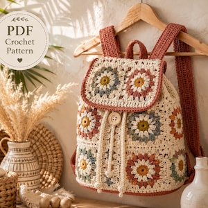 May include: A crochet backpack featuring a granny square pattern with floral motifs in cream, dusty rose, sage green, and mustard yellow. The bag has a flap closure with a single wooden button, a drawstring top, and two shoulder straps.