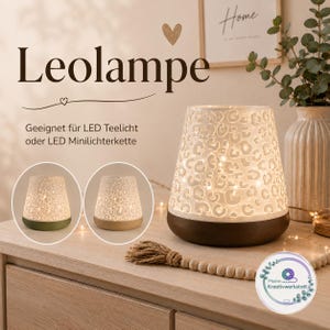 Könnte beinhalten: Eine weiße, konische, zylindrische Lampe mit ausgestanztem Leopardenmuster und einem dunkelbraunen Sockel. Die Lampe wird von innen durch kleine Lichter beleuchtet. Text auf dem Bild: Leolampe, Geeignet für LED Teelicht oder LED Minilichterkette.