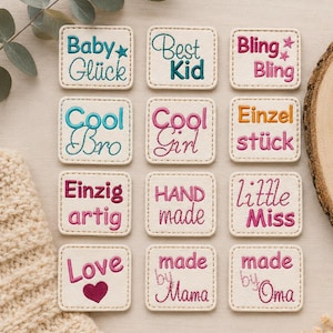 Peut inclure: Douze écussons carrés blanc cassé aux coins arrondis, chacun présentant du texte brodé de différentes couleurs. Les écussons affichent des phrases incluant Baby Glück, Best Kid, Bling Bling, Cool Bro, Cool Girl, Einzelstück, Einzigartig, HAND made, little Miss, Love, made by Mama et made by Oma.
