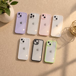 Peut inclure: Sept coques de smartphone disposées sur deux rangées, présentant une variété de cadres colorés dont lavande, transparent, rose clair, blanc, noir et vert citron. Chaque coque possède un panneau arrière transparent et une découpe pour l'objectif.