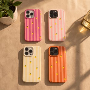 Op de afbeelding: Vier rechthoekige telefoonhoesjes in een raster, elk met een verticaal streeppatroon in roze, lichtroze, geel of oranje, versierd met kleine gele citroenpictogrammen over het oppervlak en een uitsparing voor de camera.